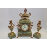 A good quality mantel clock with decorated circular dial in brass mounted onyx case flanked by a