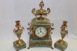 A good quality mantel clock with decorated circular dial in brass mounted onyx case flanked by a