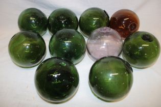 Ten various Cornish glass fishing floats in green, amber and pink tinted glass,
