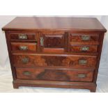 A late Victorian walnut chest with central cupboard enclosed by a small panelled door flanked by