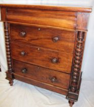 A 19th century mahogany chest of three long drawers below a shaped drawer flanked by turned columns