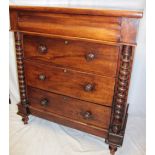 A 19th century mahogany chest of three long drawers below a shaped drawer flanked by turned columns