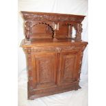 A Continental carved oak side cabinet with a single drawer in the frieze and cupboard enclosed by