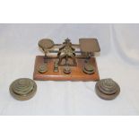 A brass postal scales on oak rectangular base together with a selection of various brass weights