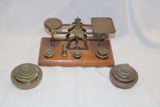 A brass postal scales on oak rectangular base together with a selection of various brass weights