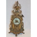 An ornamental mantel clock with decorated circular dial in brass arched pierced case