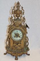 An ornamental mantel clock with decorated circular dial in brass arched pierced case