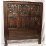 A good quality carved oak panelled double bed head decorated with mask heads and linenfold panels,