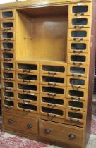 A good quality ash shop full length millinery cabinet with two base drawers below an arrangement of