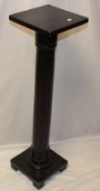 An ebonised torchere with fluted column and square top,