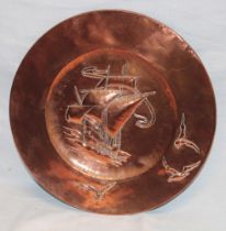 A Cornish copper circular wall plaque decorated in relief with a galleon and seagulls,
