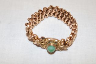A gold plated expanding bracelet with scroll decoration set central jade panel