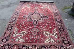 An small Eastern-style wool carpet with geometric and floral decoration on red ground 118" x 80"