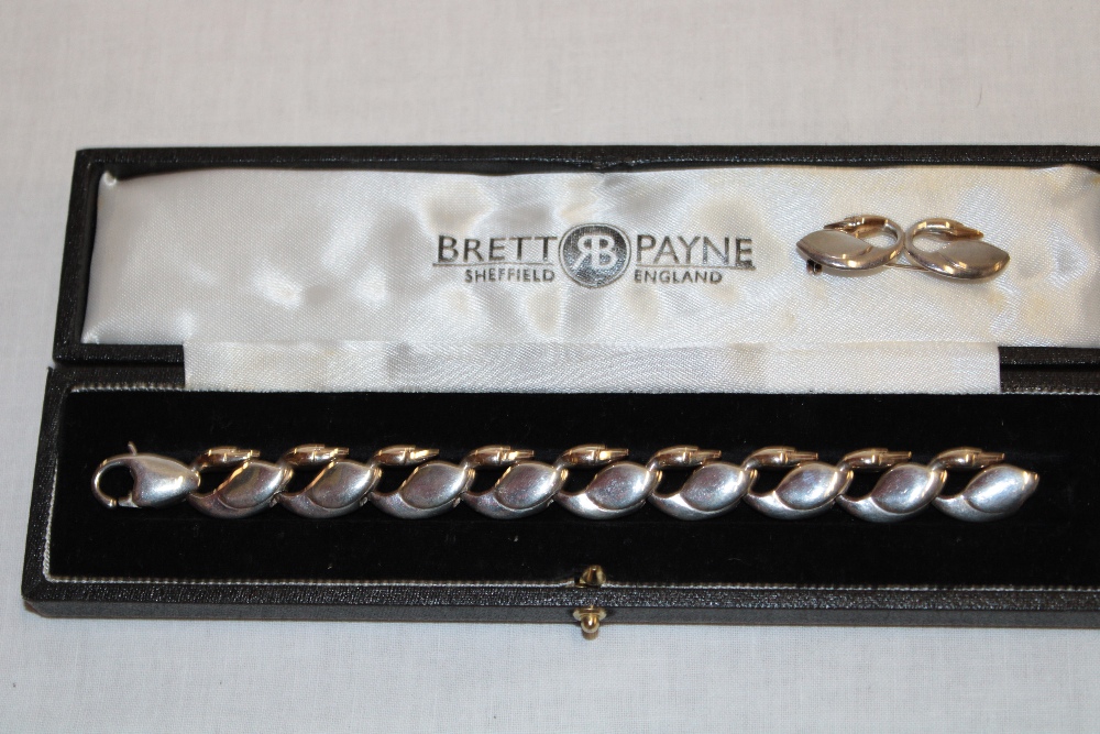 A modern silver bracelet by Brett Payne in the form of swans with 9ct gold heads together with a