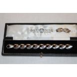 A modern silver bracelet by Brett Payne in the form of swans with 9ct gold heads together with a