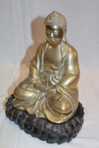 An Eastern brass seated Buddha figure on carved wood stand,