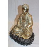 An Eastern brass seated Buddha figure on carved wood stand,