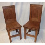 A pair of oak rustic hall chairs with plain panelled backs on square-shaped legs