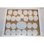 A display case containing 24 various plaster relief-decorated miniature plaques depicting classical