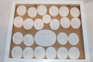 A display case containing 24 various plaster relief-decorated miniature plaques depicting classical