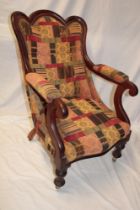 A Victorian mahogany open arm easy chair upholstered in patterned fabric on turned tapered legs