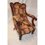 A Victorian mahogany open arm easy chair upholstered in patterned fabric on turned tapered legs