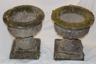 A pair of weathered garden pedestal urns on square-shaped bases 19" high (af)