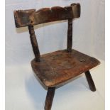 An 18th century elm child's chair of rustic form with shaped seat and turned supports,