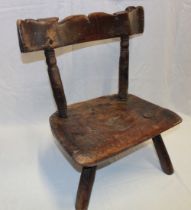 An 18th century elm child's chair of rustic form with shaped seat and turned supports,
