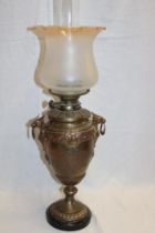 A brass pedestal oil lamp with detachable font and amber tinted opaque glass shade