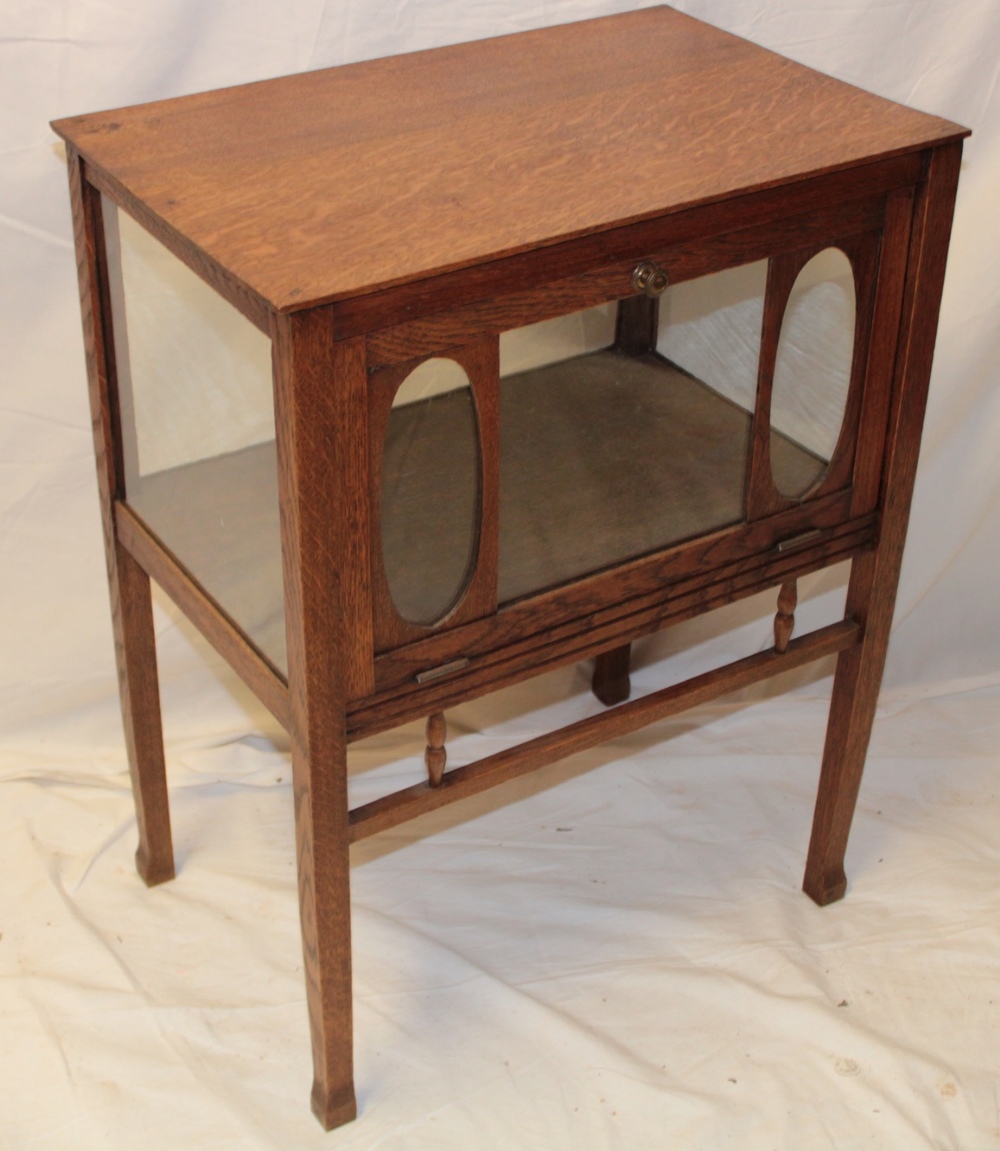 An old polished oak bijouterie-style four-sided display cabinet with compartment enclosed by a