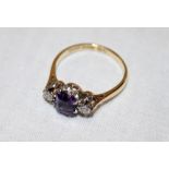 An 18ct gold dress ring with platinum shoulders set a central amethyst flanked by two diamonds (2.
