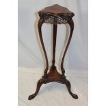 An Edwardian carved mahogany triangular plant stand on scroll-shaped legs (af)