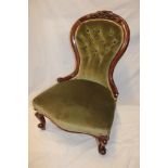 A Victorian carved mahogany easy chair upholstered in green buttoned fabric on scroll legs