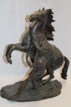 A bronze figure of a rearing horse and male figure on rustic oval base,