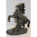 A bronze figure of a rearing horse and male figure on rustic oval base,