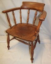 A polished elm captain's-style chair with spindle back and shaped seat on turned legs