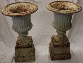 A pair of painted cast iron classical-shaped garden urns on fluted stems and square plinths 27"