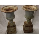 A pair of painted cast iron classical-shaped garden urns on fluted stems and square plinths 27"