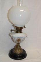 An Edwardian brass oil lamp with floral opaque glass reservoir and spherical shade
