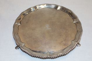 A George III silver circular waiter tray with decorated edge and engraved armorial crest on three