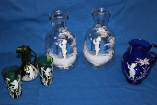 A pair of clear glass tapered carafes with Mary Gregory-style painted decoration depicting young