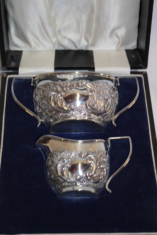 A late Victorian silver two-handled sugar basin with raised decoration together with matching cream