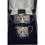 A late Victorian silver two-handled sugar basin with raised decoration together with matching cream