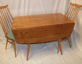 An Ercol pale elm drop-leaf dining table on square tapered legs together with a pair of