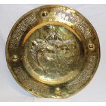 A brass circular embossed wall plaque, the centre decorated in relief with two fish,