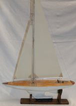 A painted wood model pond yacht with weighted keel and nylon sails,