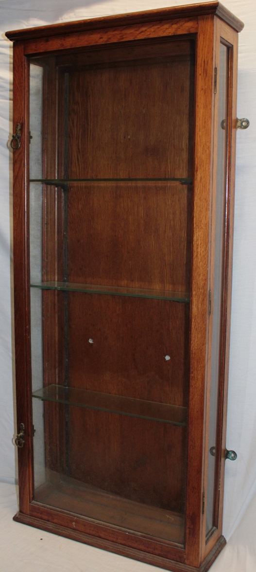 An oak wall mounted glazed collector's cabinet with shelves enclosed by a single glazed door,