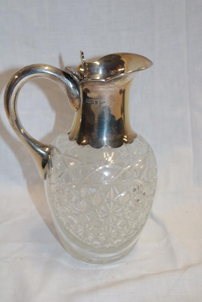 A George V cut-glass and silver mounted claret jug with silver handle and hinged top, 8½" high,