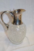 A George V cut-glass and silver mounted claret jug with silver handle and hinged top, 8½" high,